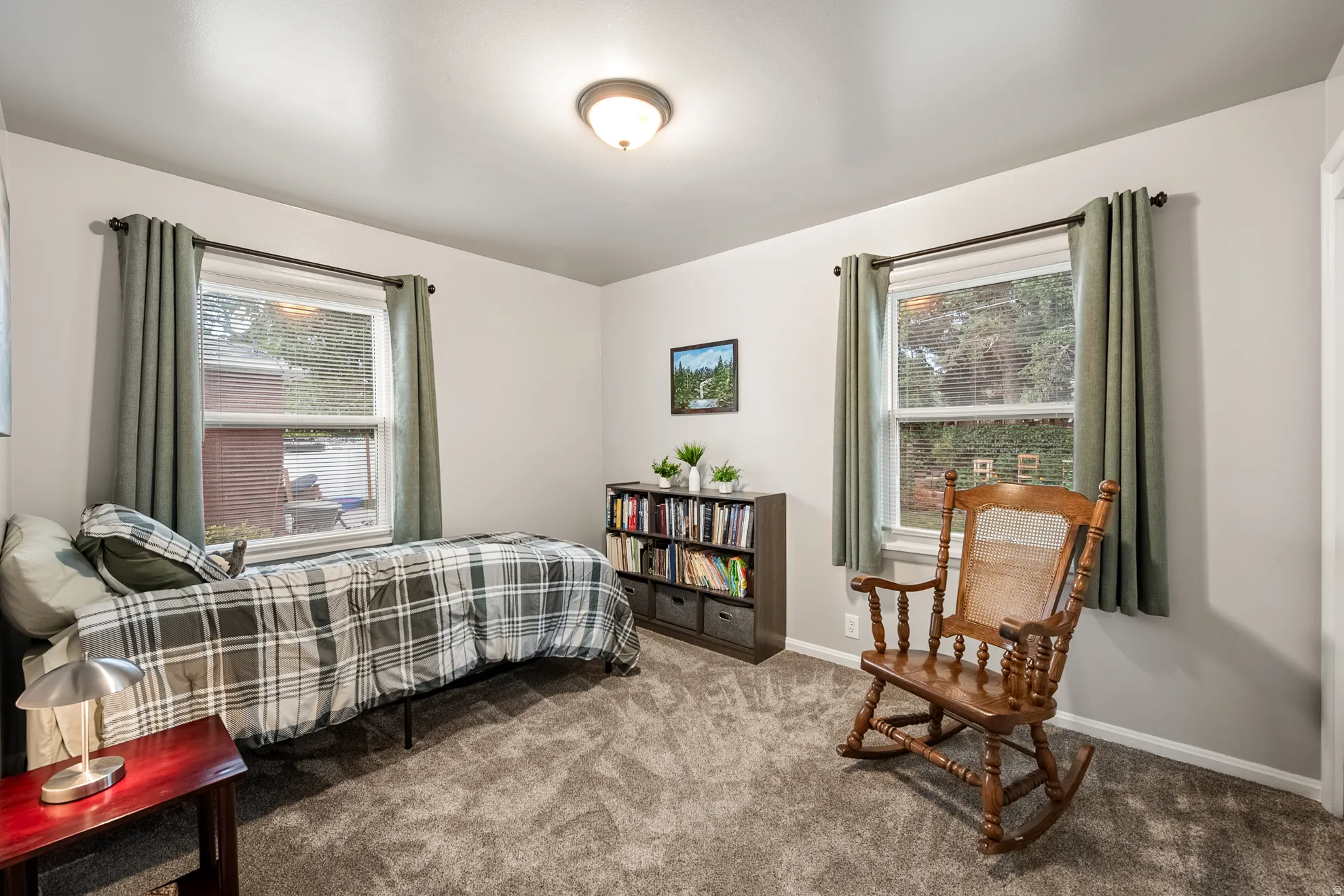Bedroom featuring light gray walls, plush gray carpeting, and two windows with white trim