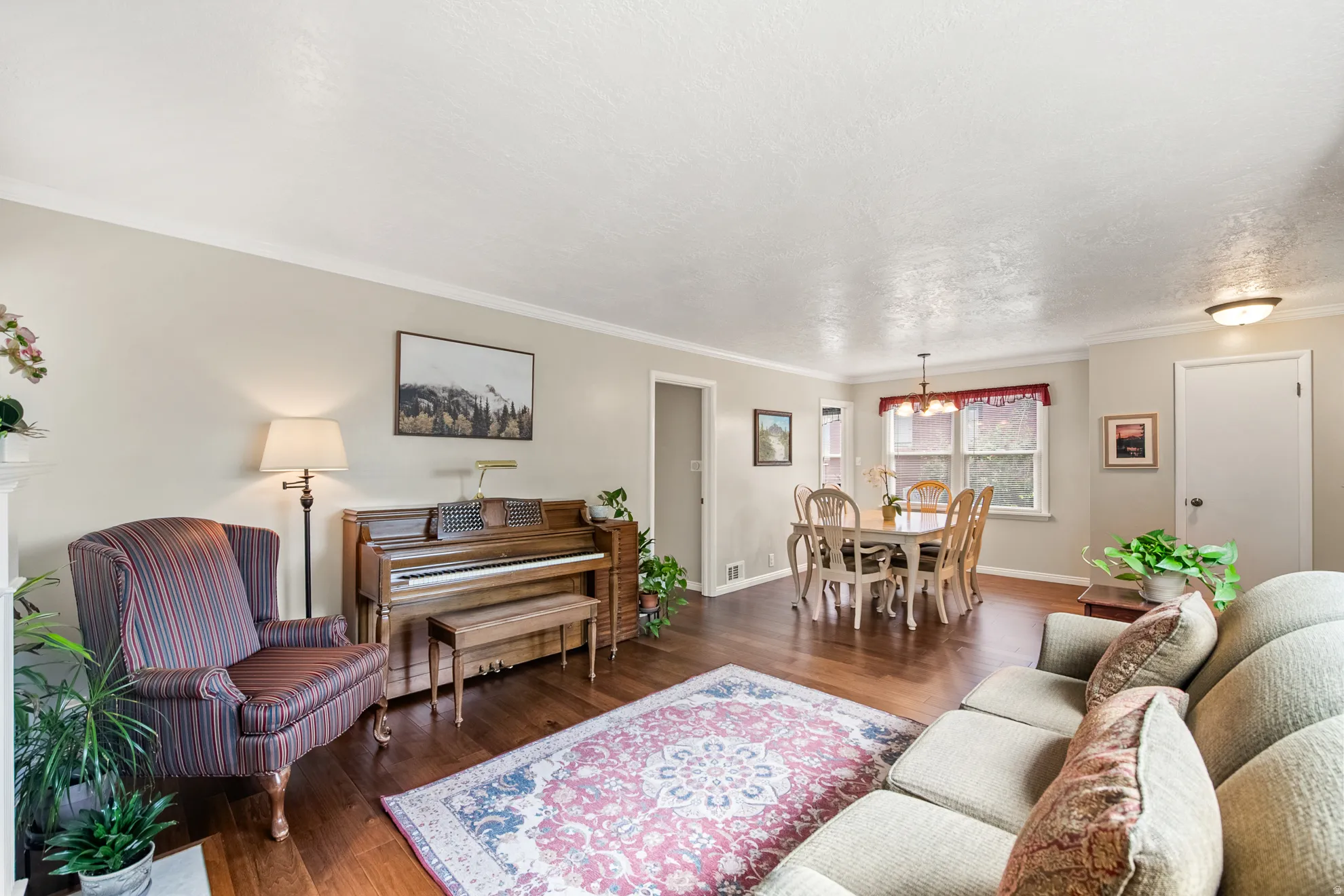 Open-concept living and dining area featuring wood-finish flooring, neutral wall tones, and crown molding