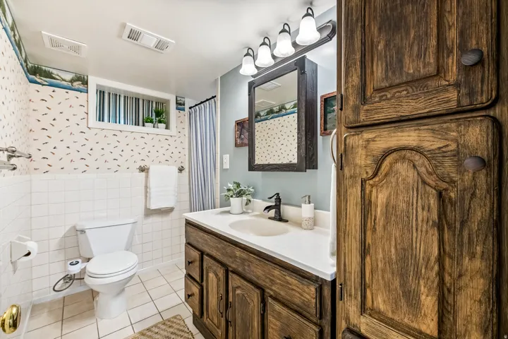 Bathroom featuring a wood-finish vanity with an integrated sink, white countertop, and a dark bronze faucet