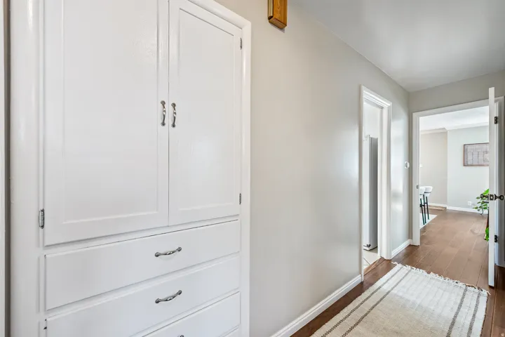 White built-in cabinetry with silver-tone hardware, light gray wall paint, and wood-finish flooring