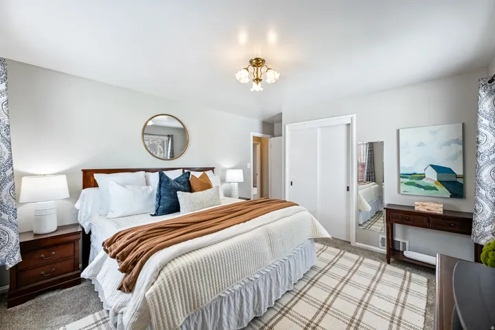 Recessed lighting, wood-finish nightstands, full-height sliding closet doors, and patterned area rug