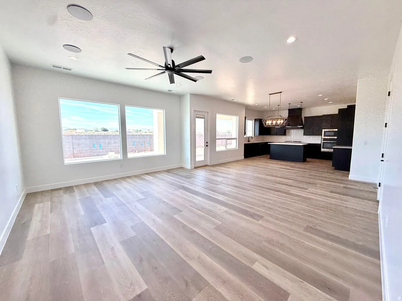 Open-concept living space featuring wood-finish flooring, recessed lighting, and a contemporary ceiling fan