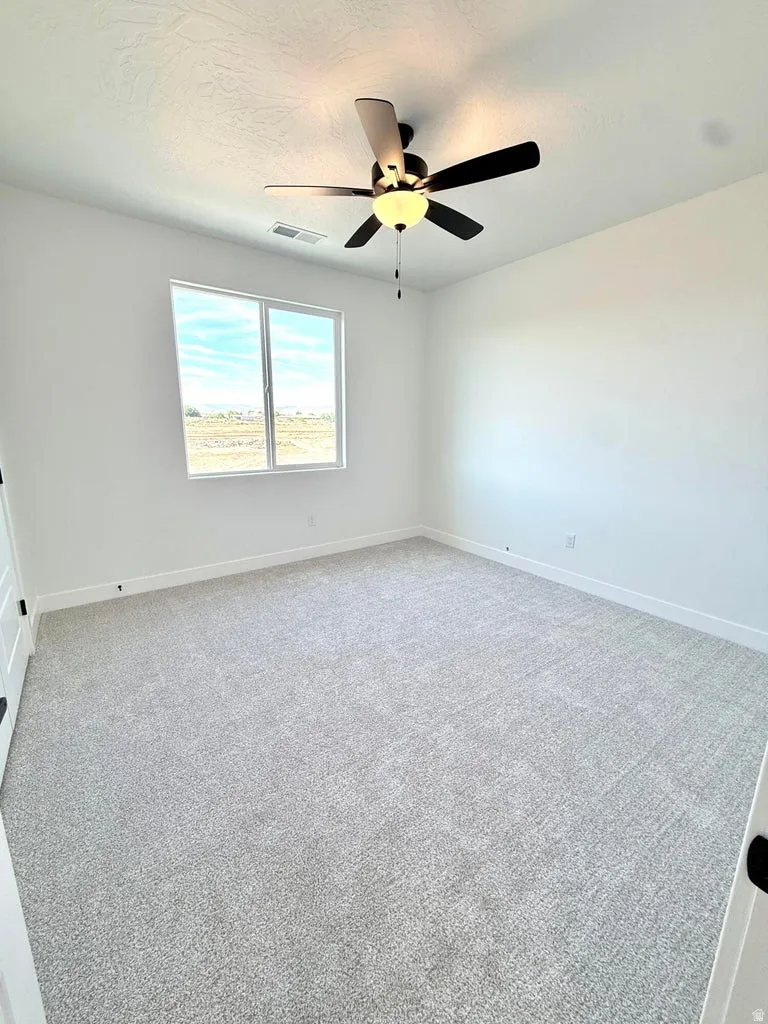 Spacious room featuring light-colored carpeting, a contemporary ceiling fan with integrated lighting, and a double window