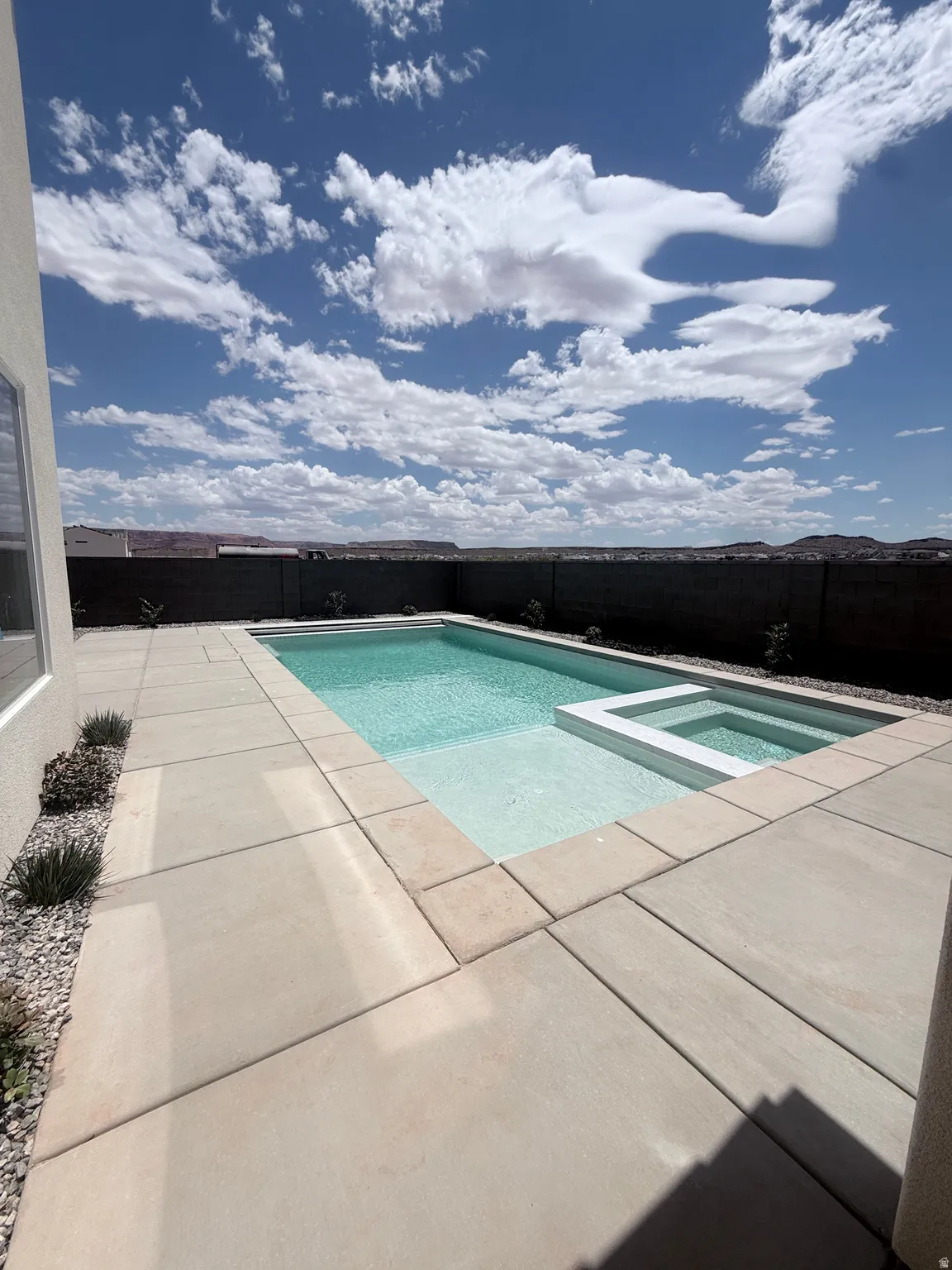 Outdoor swimming pool and spa with integrated steps, surrounded by large format concrete pavers