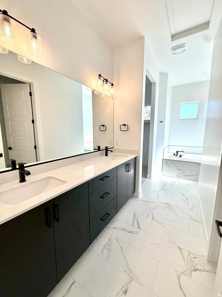 Bathroom vanity featuring dual integrated sinks, dark wood-finish cabinetry with matte black hardware, and an expansive wall-mounted mirror