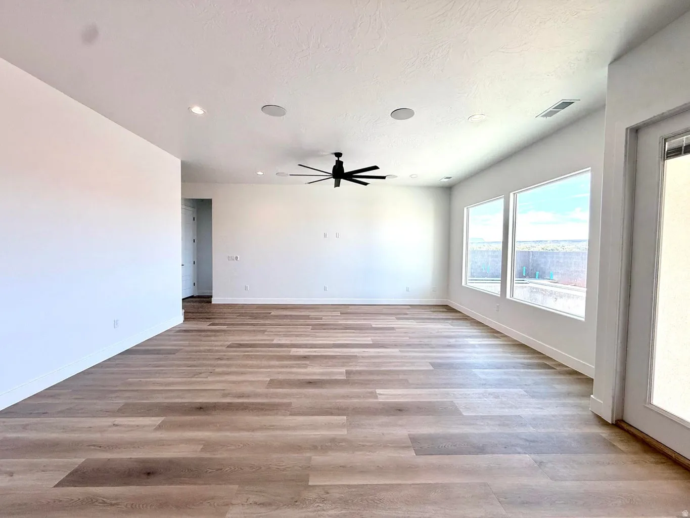 Spacious room featuring wood-finish flooring, recessed lighting, and a contemporary ceiling fan