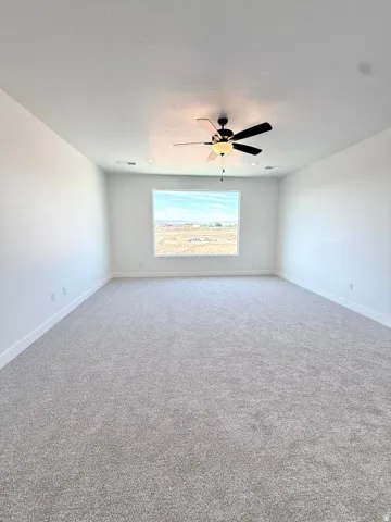 Spacious room featuring a large window, light-colored carpet flooring, white painted walls, a ceiling fan, and recessed lighting