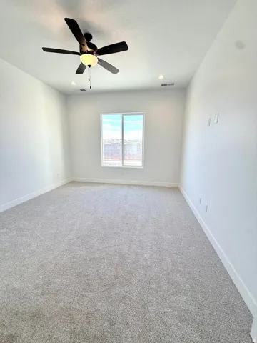 Spacious room featuring neutral carpeting, white walls, a large window, a ceiling fan, and recessed lighting