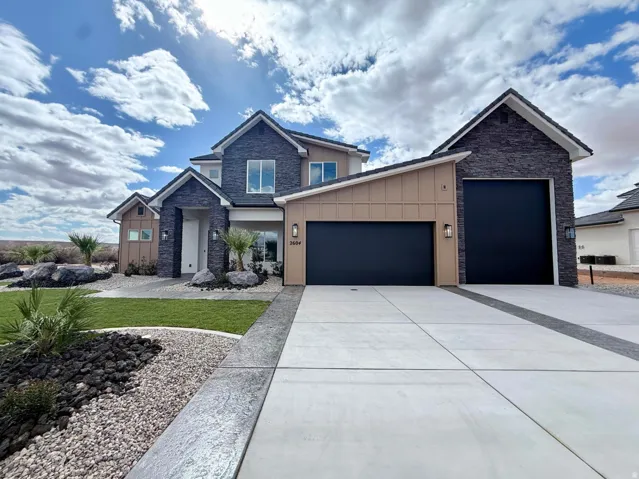 Modern dwelling featuring a stone facade, beige vertical siding, and a concrete driveway