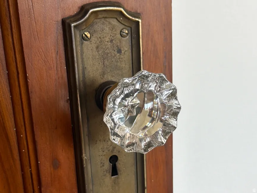 Wood-panel door featuring a faceted crystal doorknob with an aged brass backplate and exposed keyhole