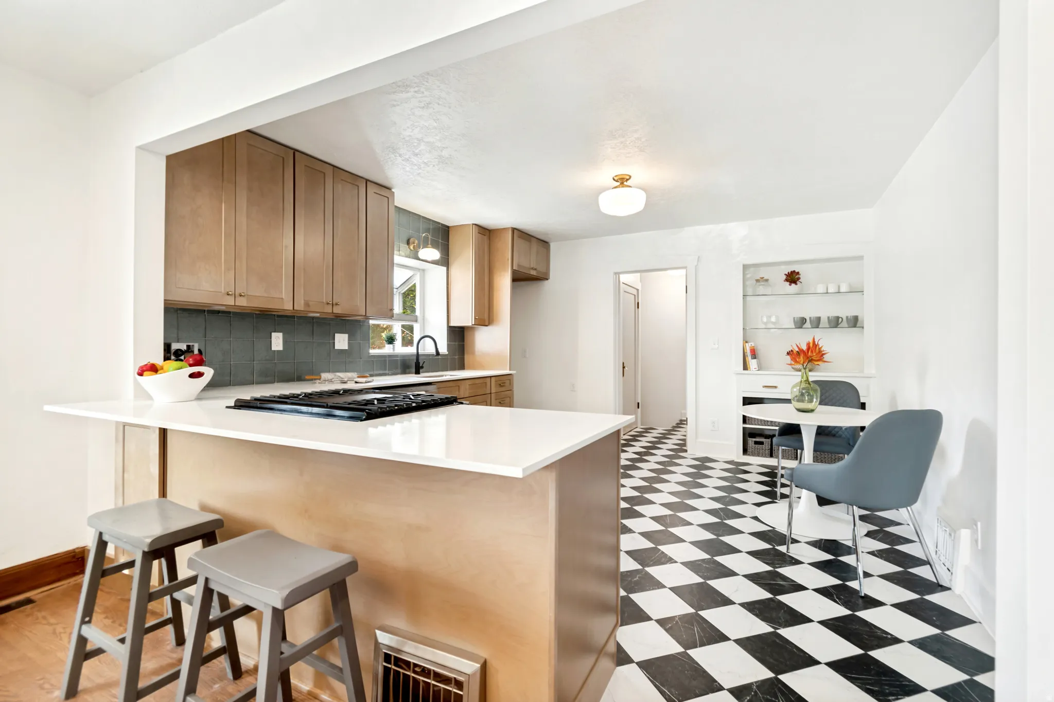 Open-concept kitchen featuring light wood cabinetry, a built-in gas range, white countertops, and a full-height tile backsplash
