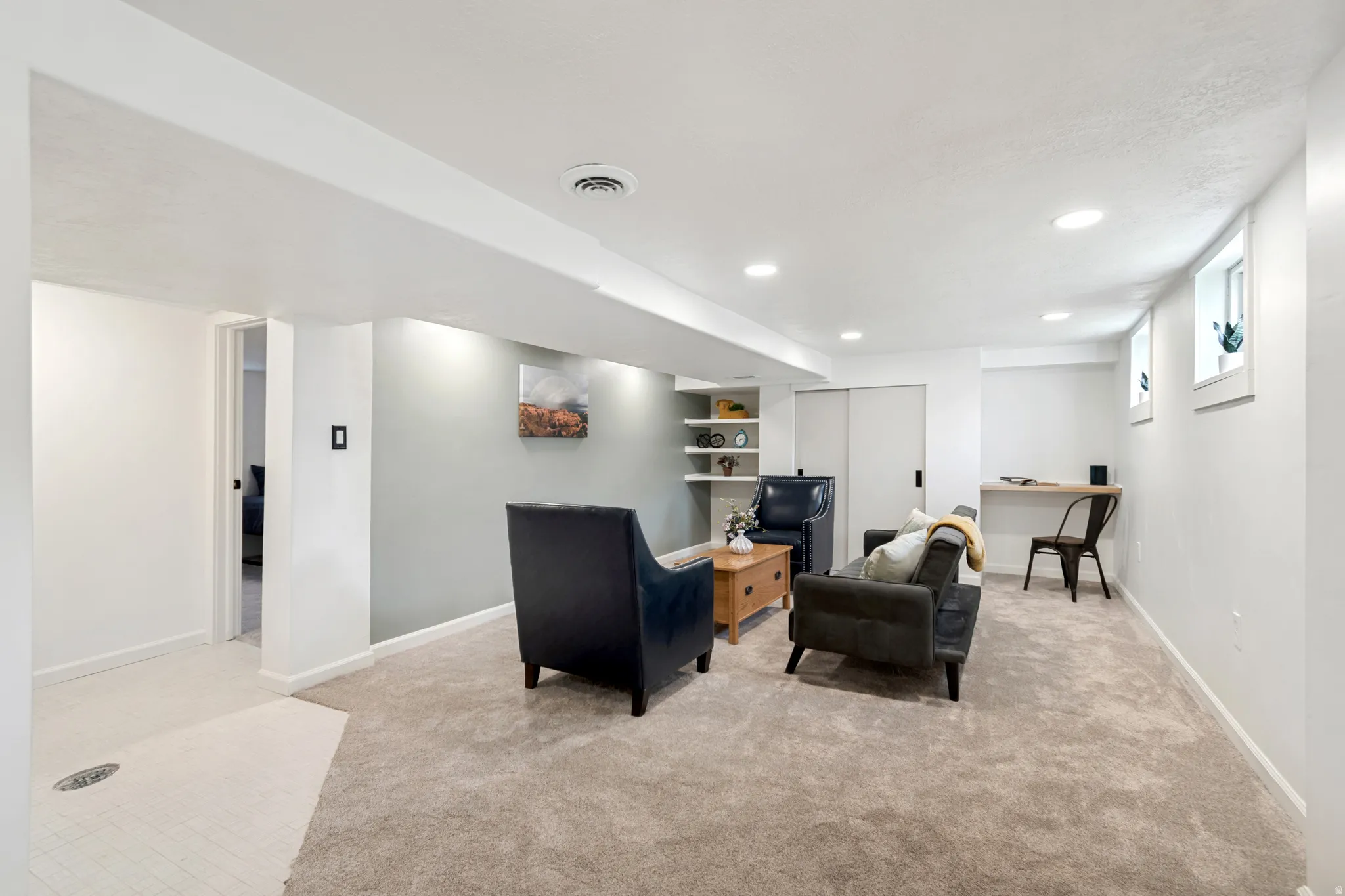 Lower level space featuring recessed lighting, plush carpeting, built-in shelving, and a wall-mounted desk