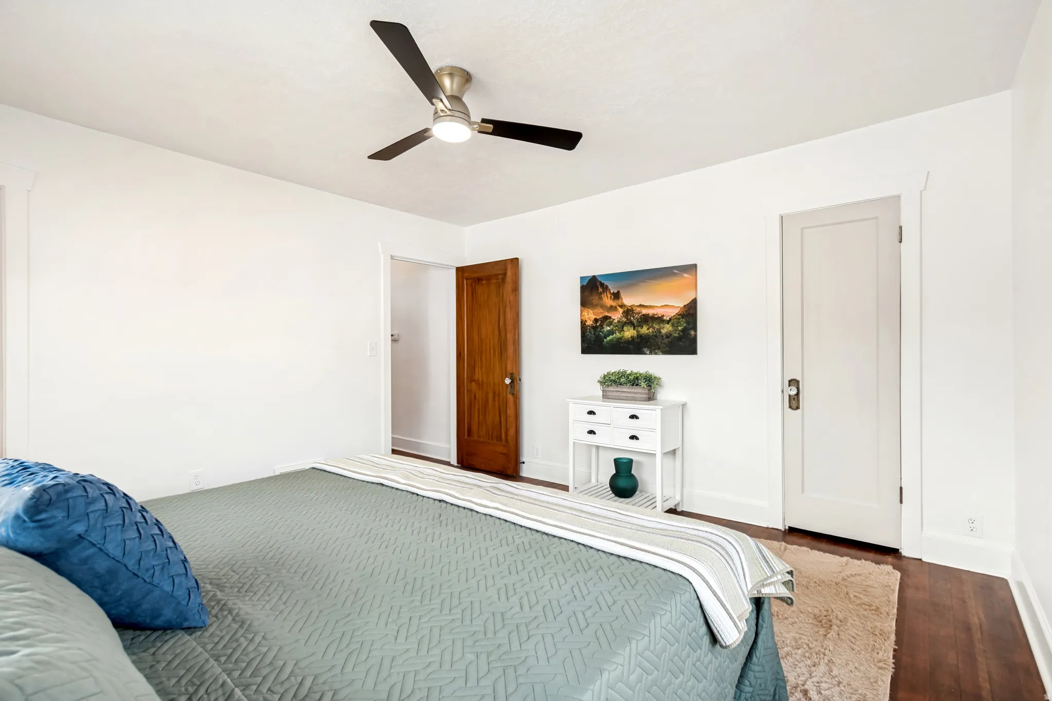 Master Bedroom. White-painted room featuring wood-finish flooring, a ceiling fan with integrated lighting, and a solid wood interior door