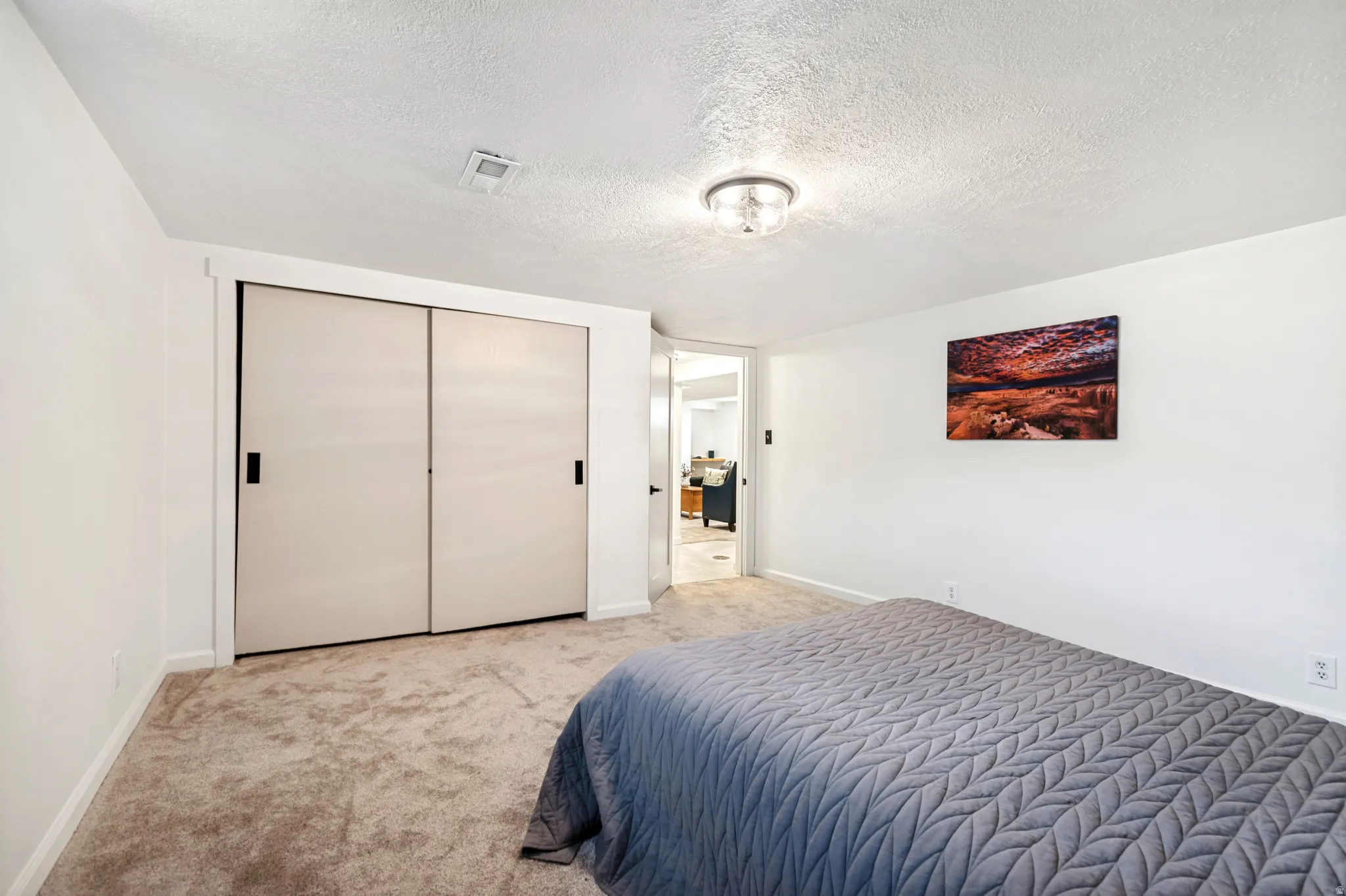 Bedroom 3. Carpeted room featuring a ceiling-mounted light fixture, white walls, and a closet with sliding doors