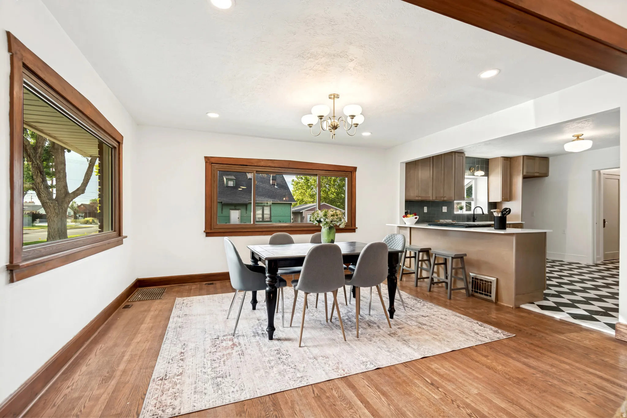 Dining area featuring wood-finish flooring, two large windows with wood trim, recessed lighting, and a chandelier