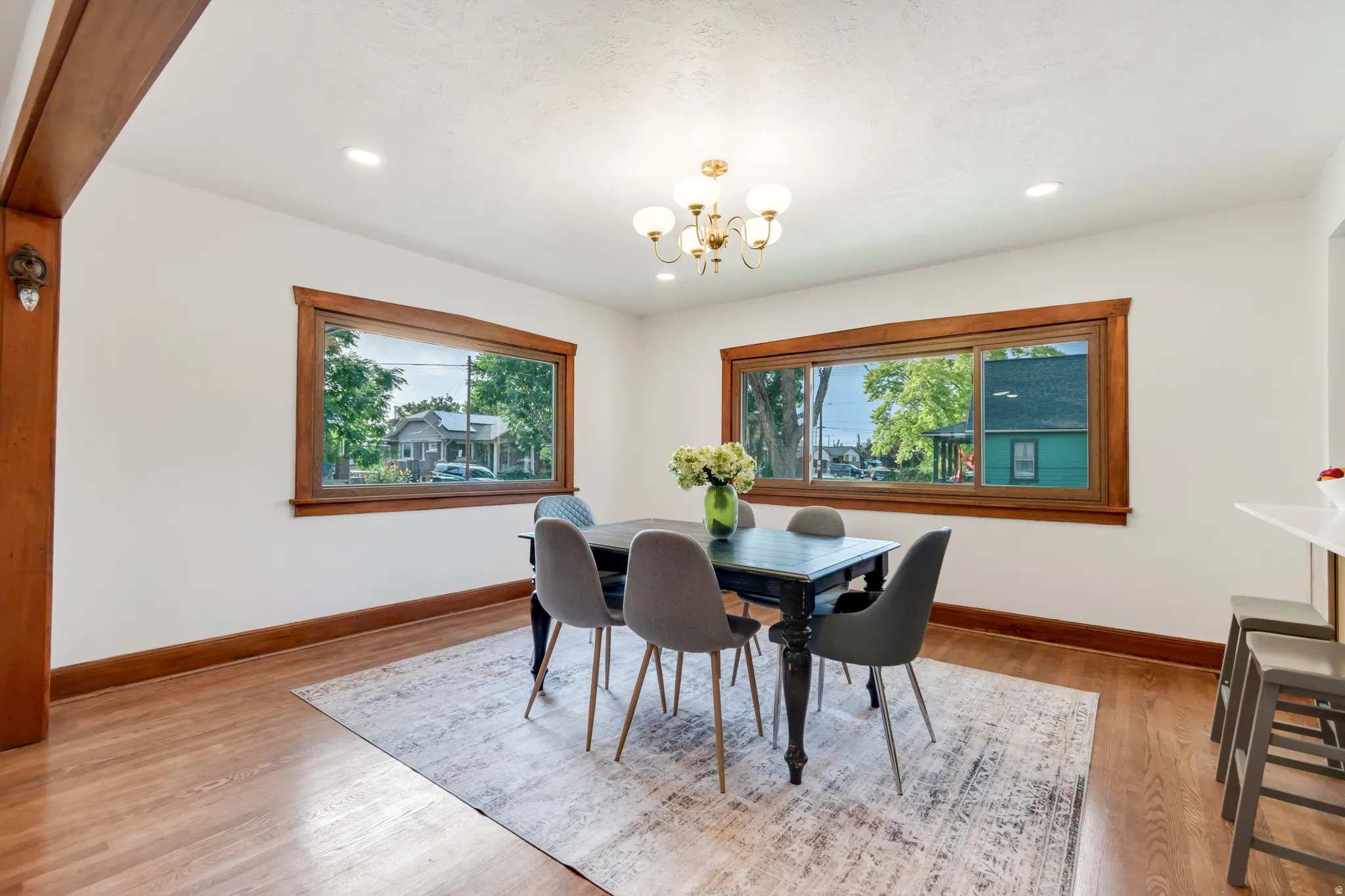 Bright dining space featuring wood-finish flooring, extensive wood trim, and two large windows