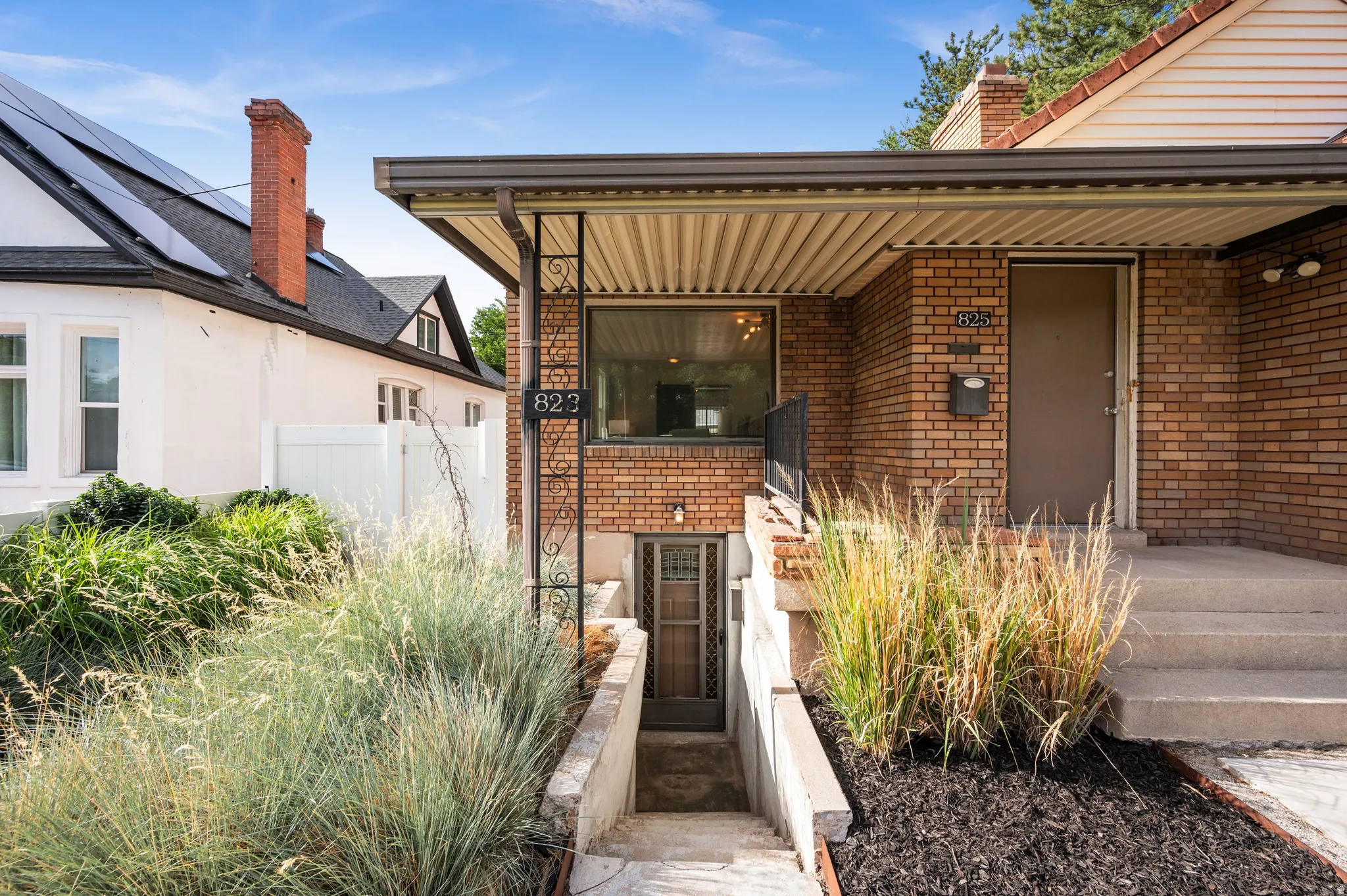 Brick facade residential exterior with a covered entry, concrete steps, and integrated landscaping