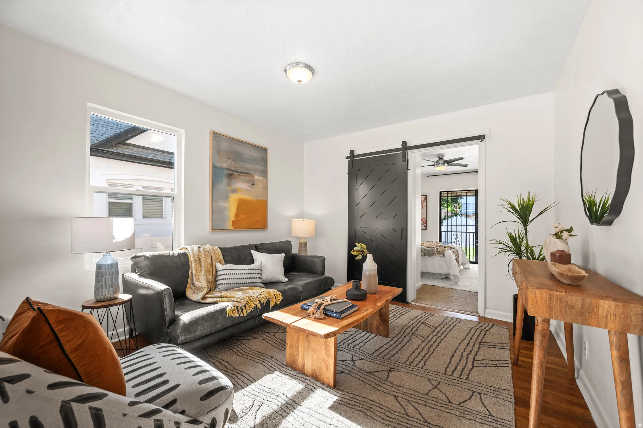Living area featuring white walls, a wood-finish floor, and a black barn door leading to an additional room