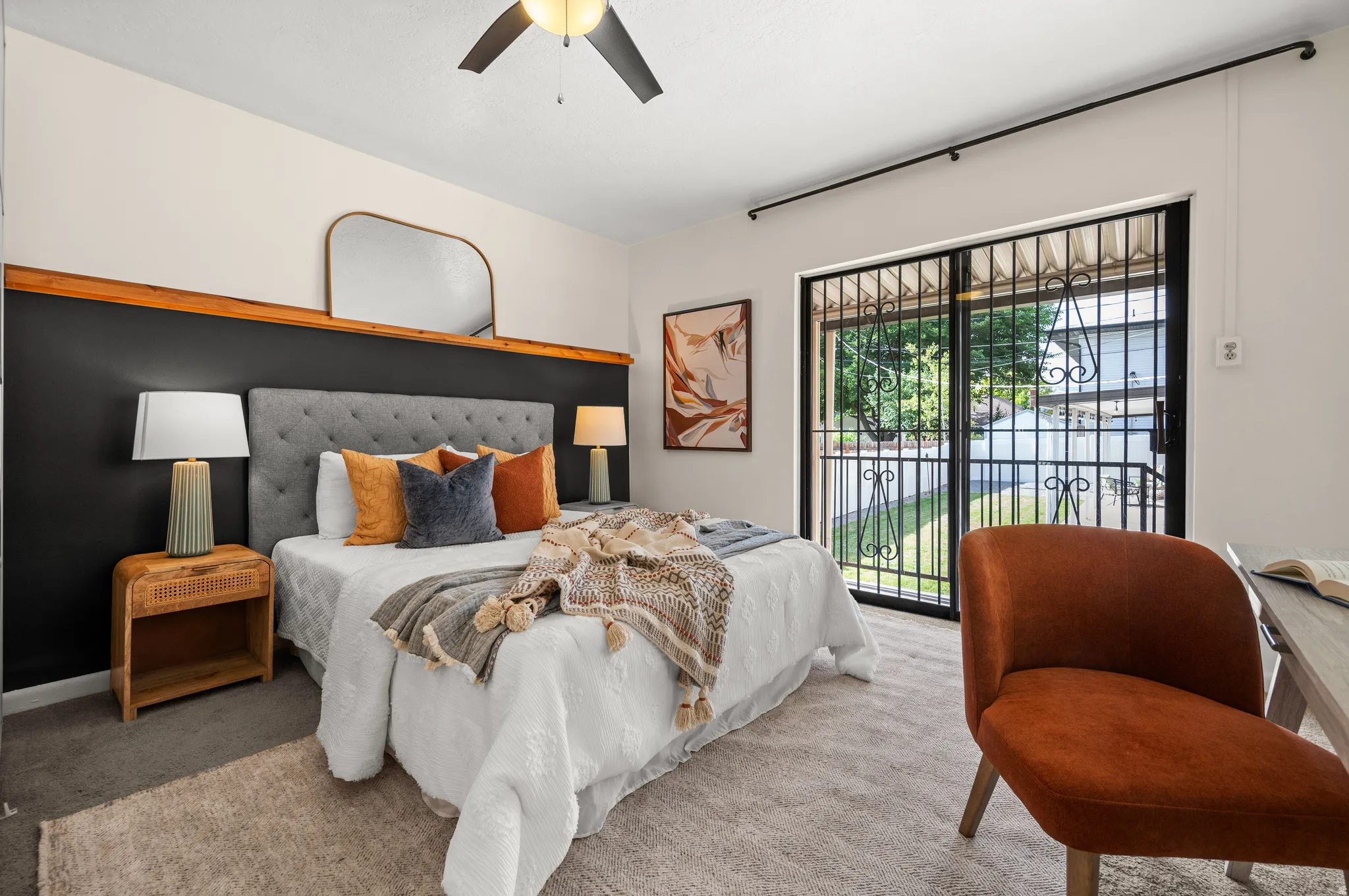 Bedroom featuring a tufted headboard, dark accent wall with wood trim, and a ceiling fan