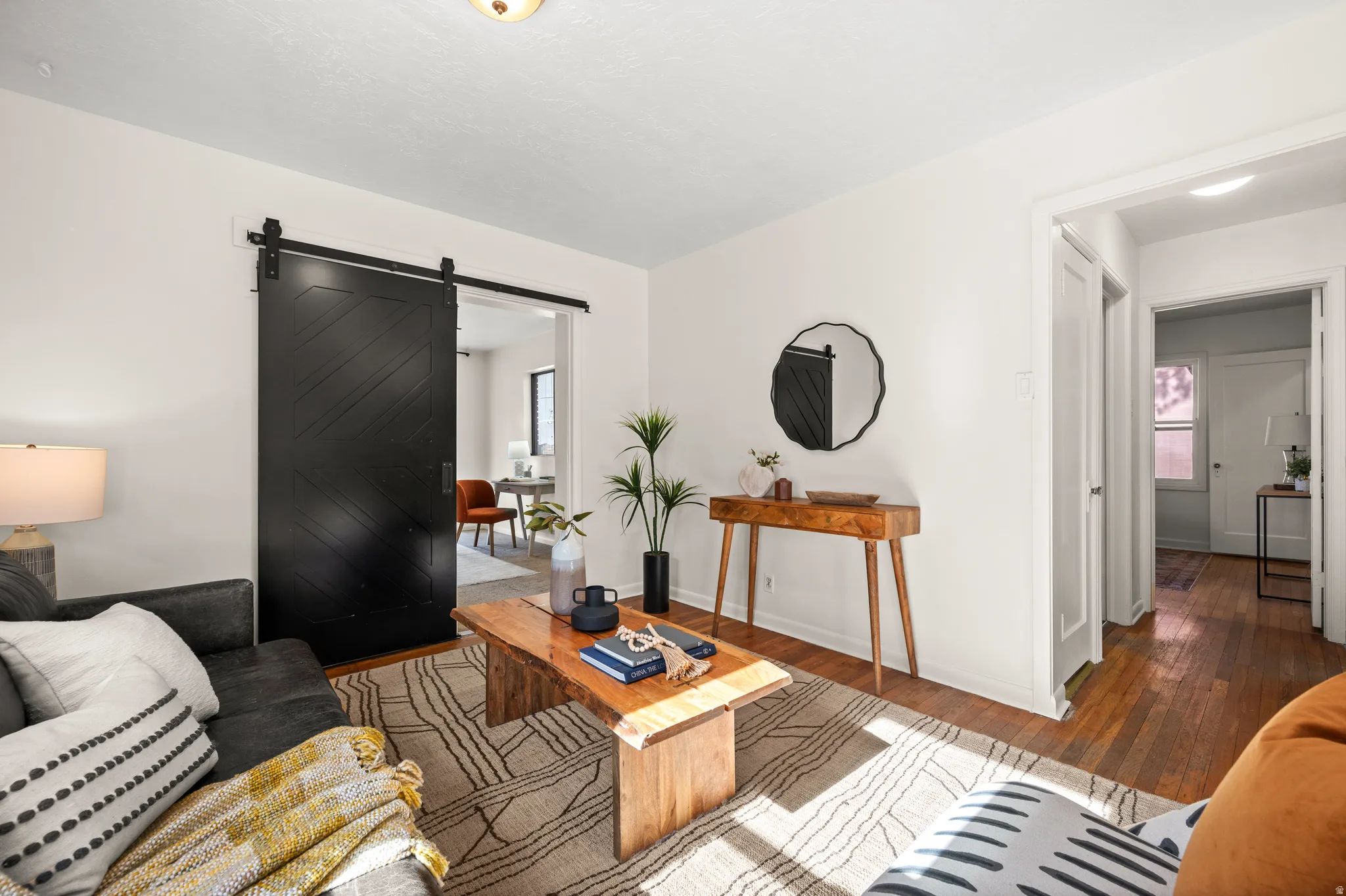 Living space featuring white walls, wood-finish flooring, and a large black barn door