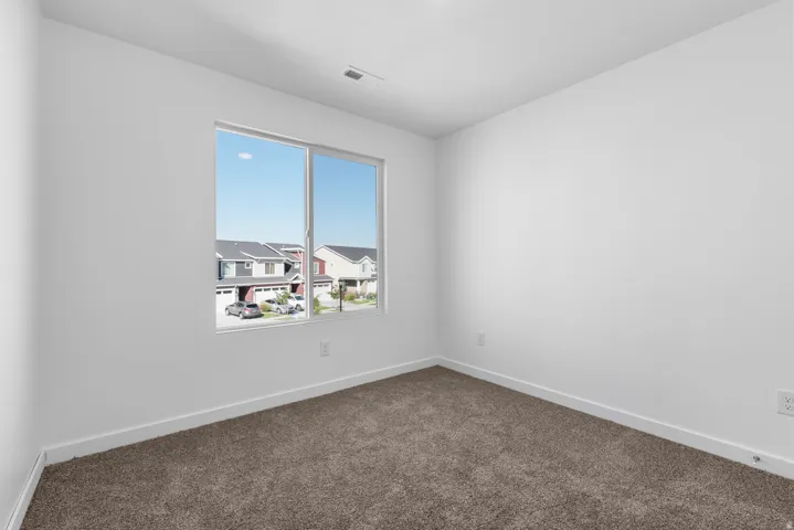Bright interior room featuring a large window, neutral wall paint, white trim, and brown carpet flooring