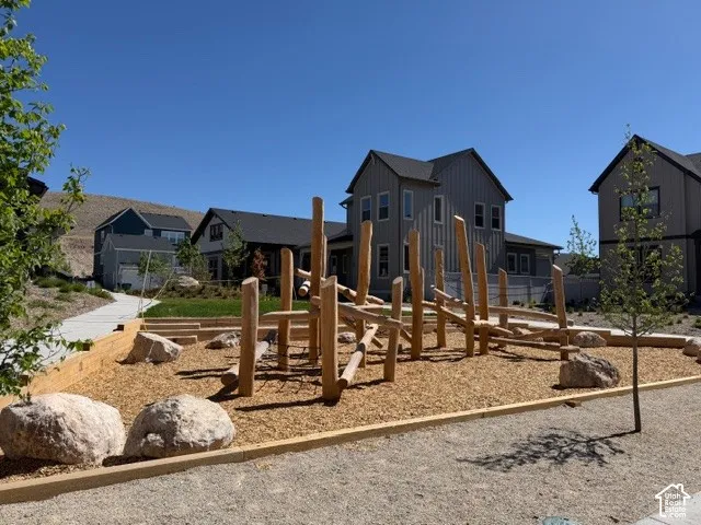 Community recreational area featuring natural wood play structures, large boulders, and woodchip surfacing