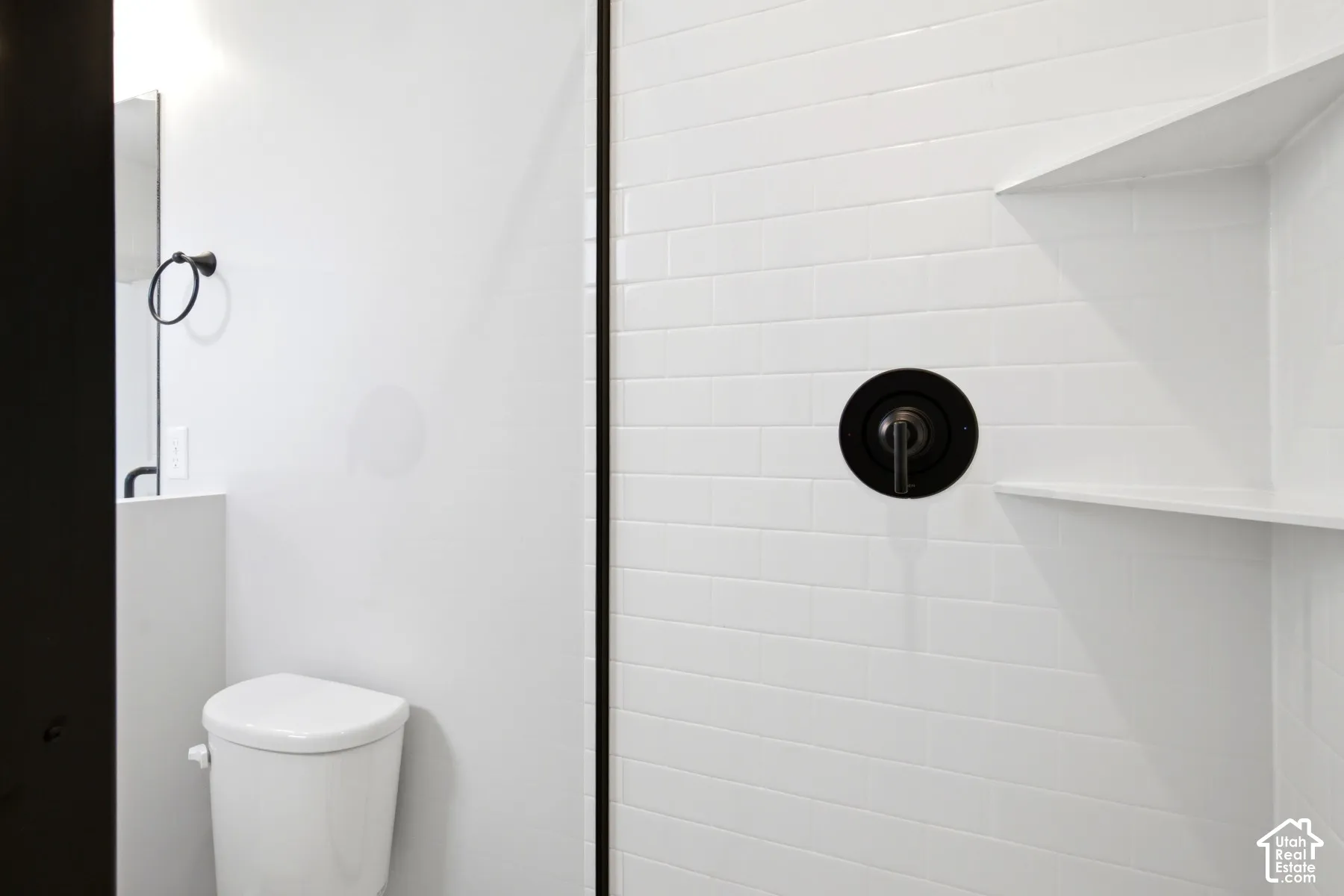 Shower with white subway tile surround, recessed shelving, and a dark bronze shower fixture