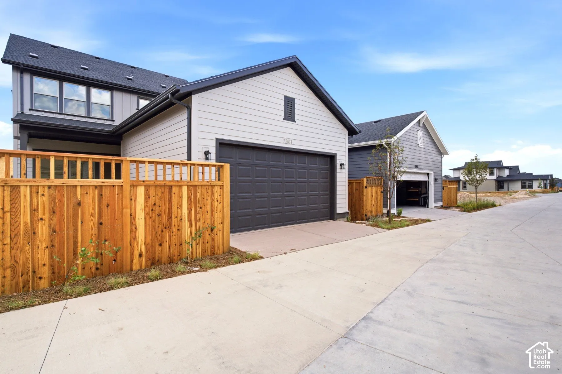 Contemporary residence featuring light gray siding, dark trim, and a dark asphalt shingle roof