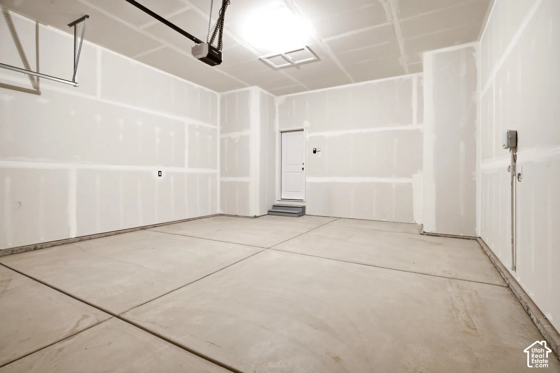 Spacious garage featuring a concrete floor, high ceilings, and an automatic garage door opener system
