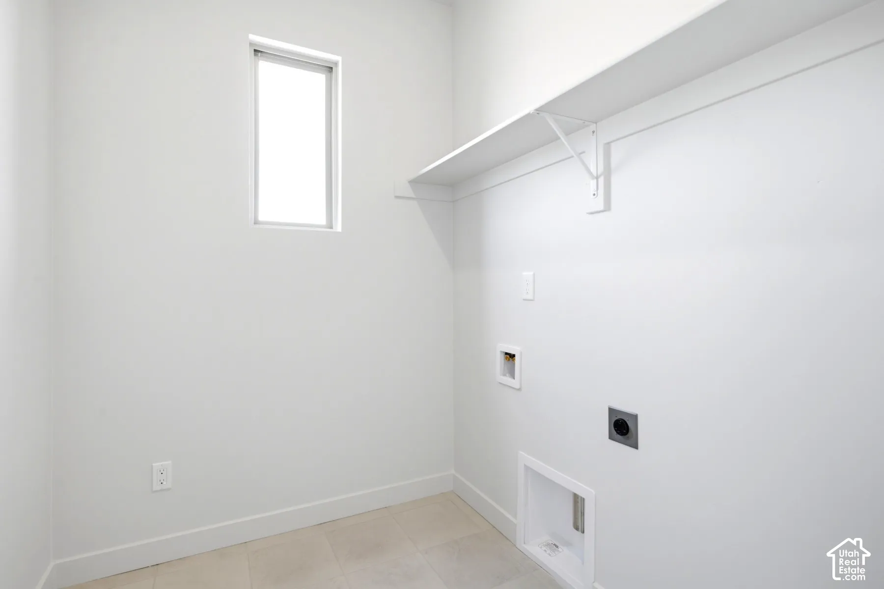 Utility room featuring a window, built-in shelving, and light-toned tile flooring