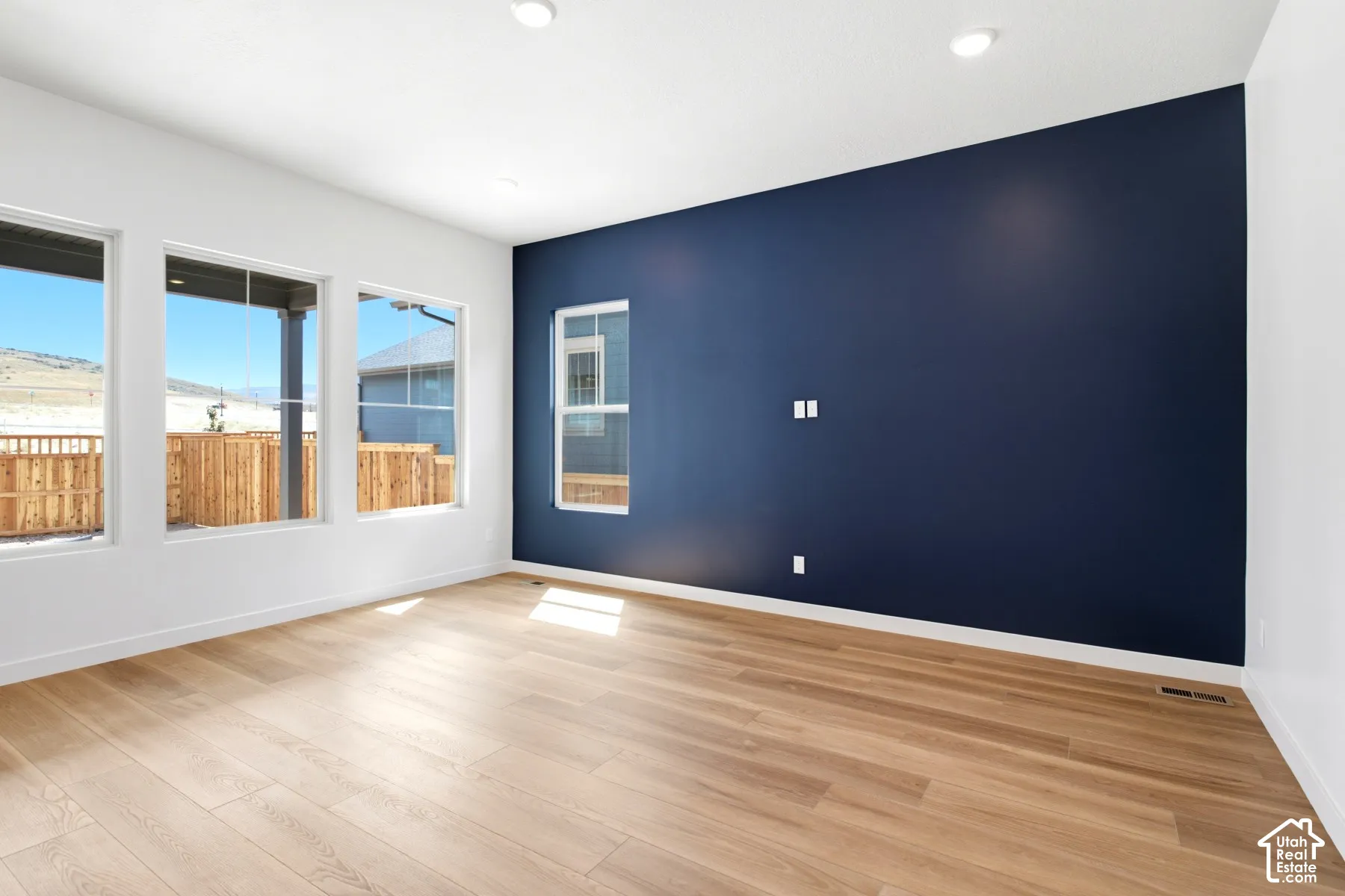 Spacious room featuring wood-finish flooring and a striking accent wall