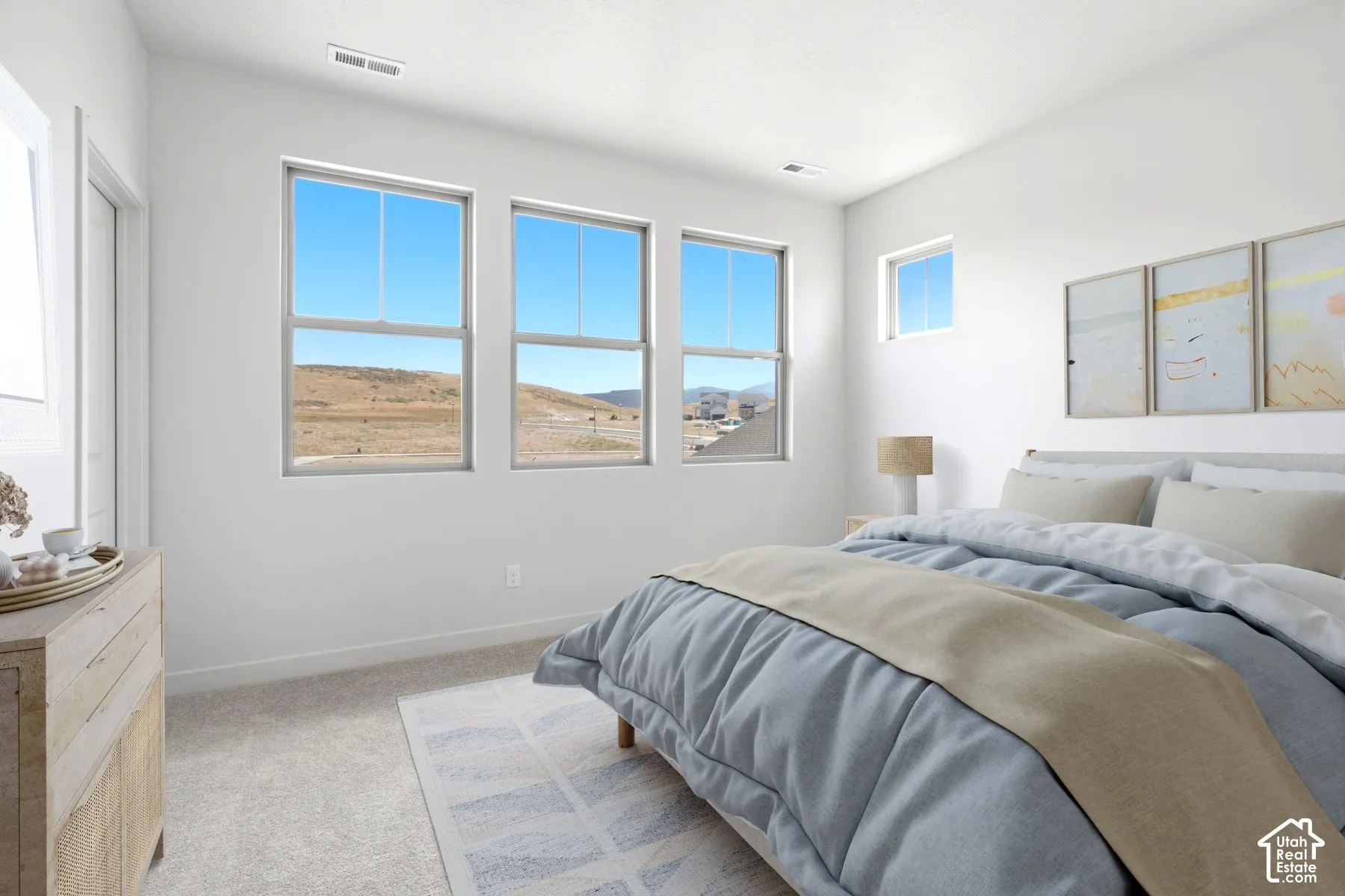 Bright bedroom featuring three large windows, an additional small window, light gray carpet, and white painted walls