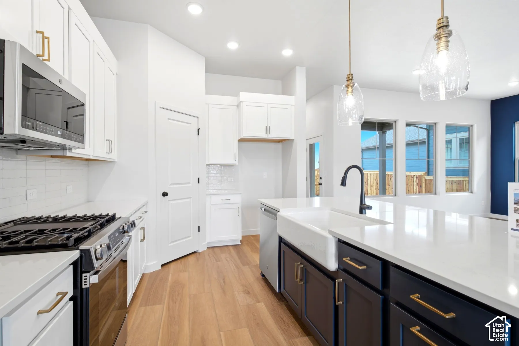 Gourmet kitchen featuring a white farmhouse sink, black faucet, and two-tone cabinetry with gold-finish hardware