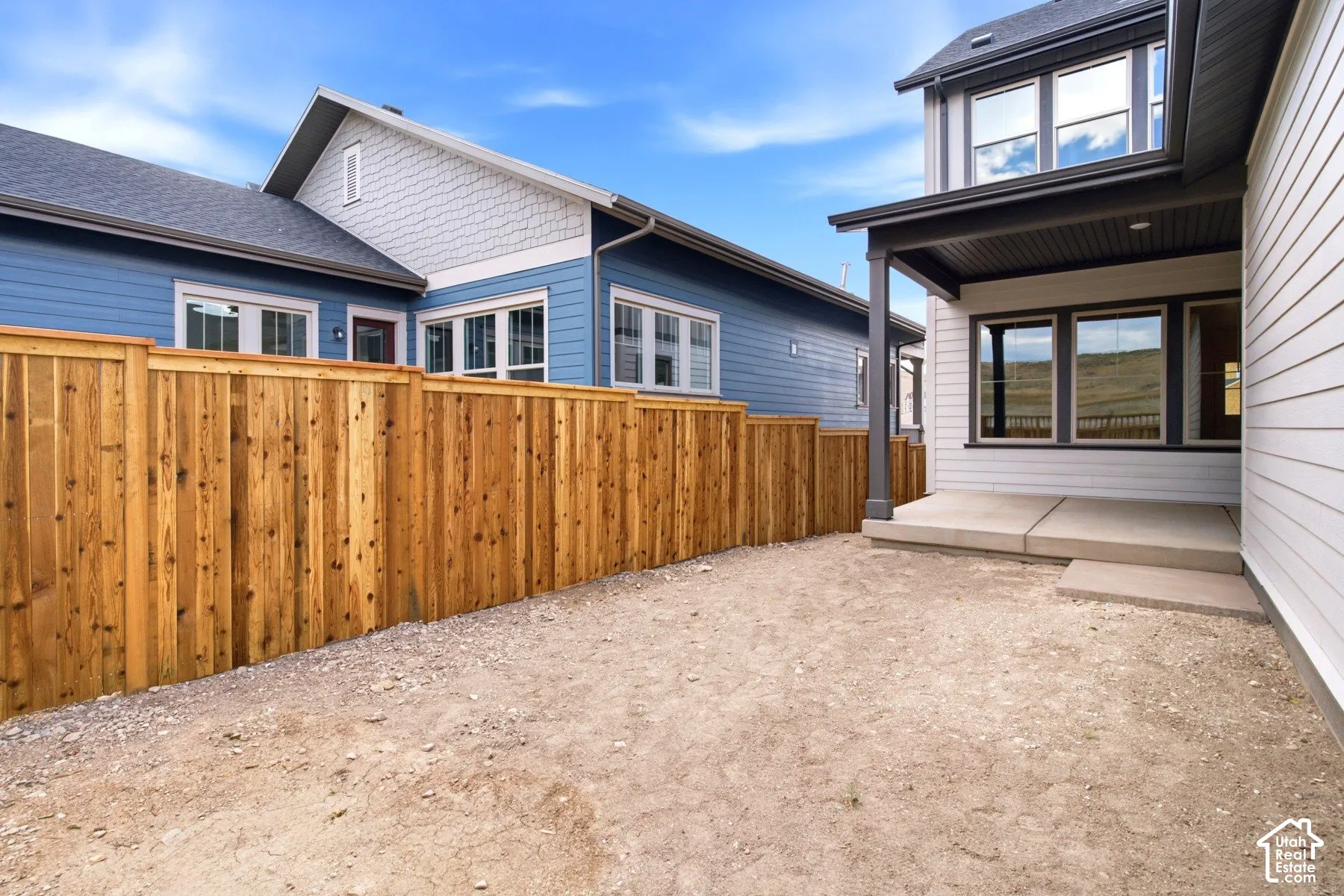 Spacious backyard area featuring a wood fence, concrete patio, and durable siding exterior