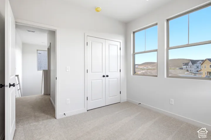 Bright room featuring two large windows, white walls, and light-colored carpet flooring
