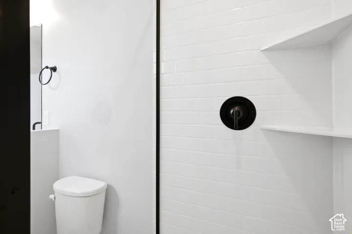 Shower with white subway tile surround, recessed shelving, and a dark bronze shower fixture