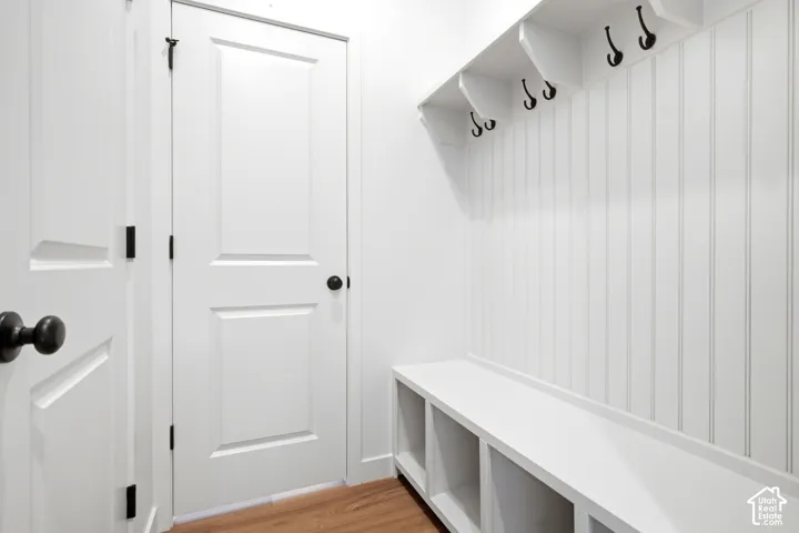 Built-in mudroom bench with cubby storage, beadboard wall paneling, and black coat hooks