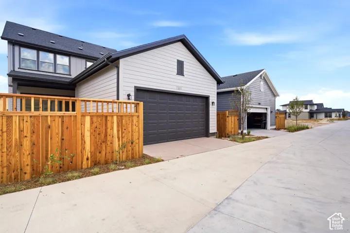 Contemporary residence featuring light gray siding, dark trim, and a dark asphalt shingle roof