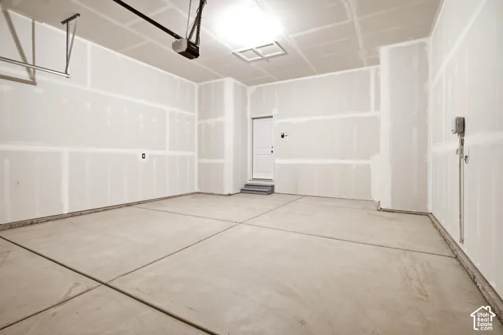 Spacious garage featuring a concrete floor, high ceilings, and an automatic garage door opener system