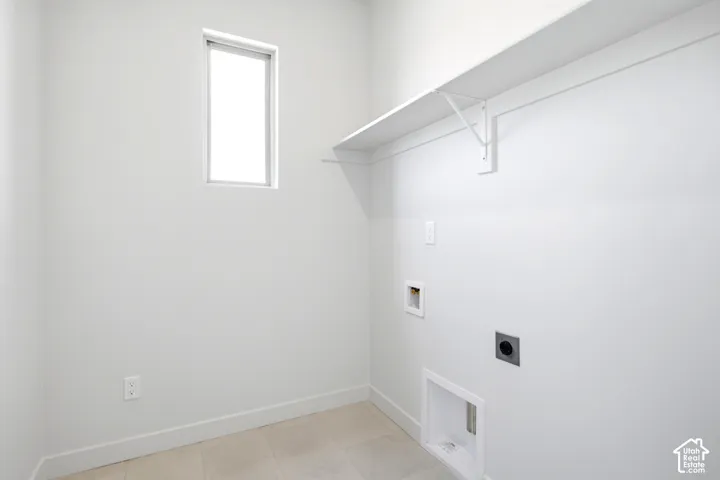 Utility room featuring a window, built-in shelving, and light-toned tile flooring