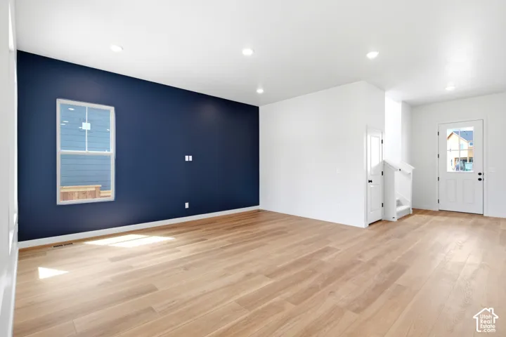 Open-concept living space featuring wood-finish flooring, recessed lighting, and a prominent accent wall