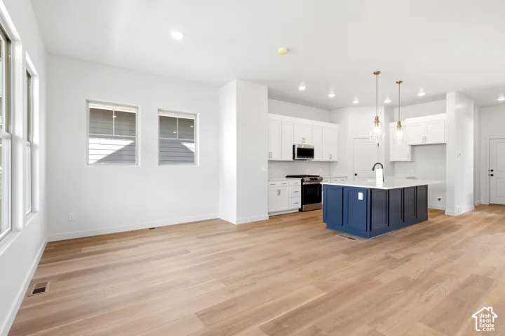 Open-concept living space featuring wood-finish flooring, recessed lighting, and white walls