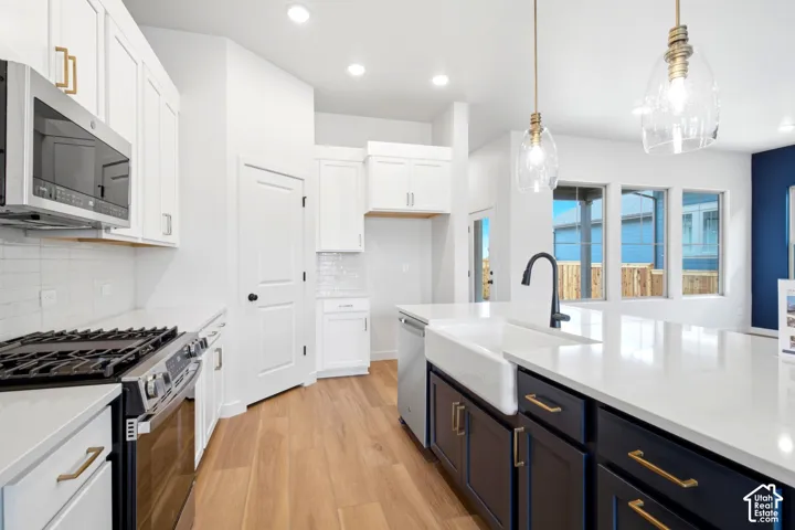 Gourmet kitchen featuring a white farmhouse sink, black faucet, and two-tone cabinetry with gold-finish hardware