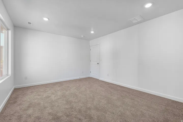 Expansive room featuring neutral-toned carpeting, white walls, and recessed lighting
