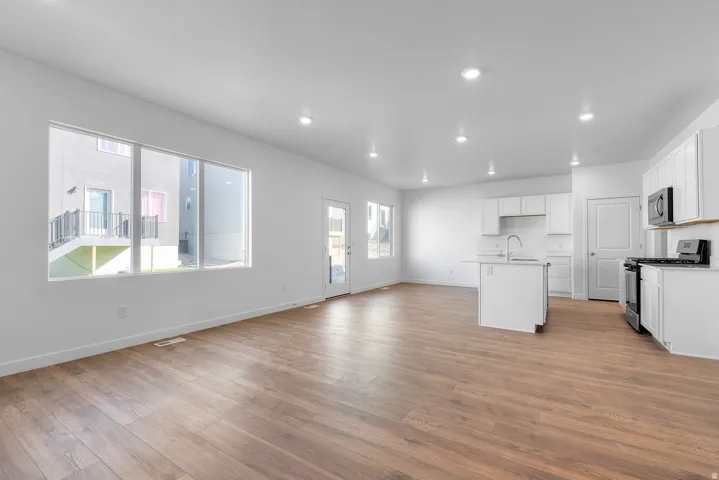 Open-concept living area featuring wood-finish flooring, recessed lighting, and a kitchen with white cabinetry