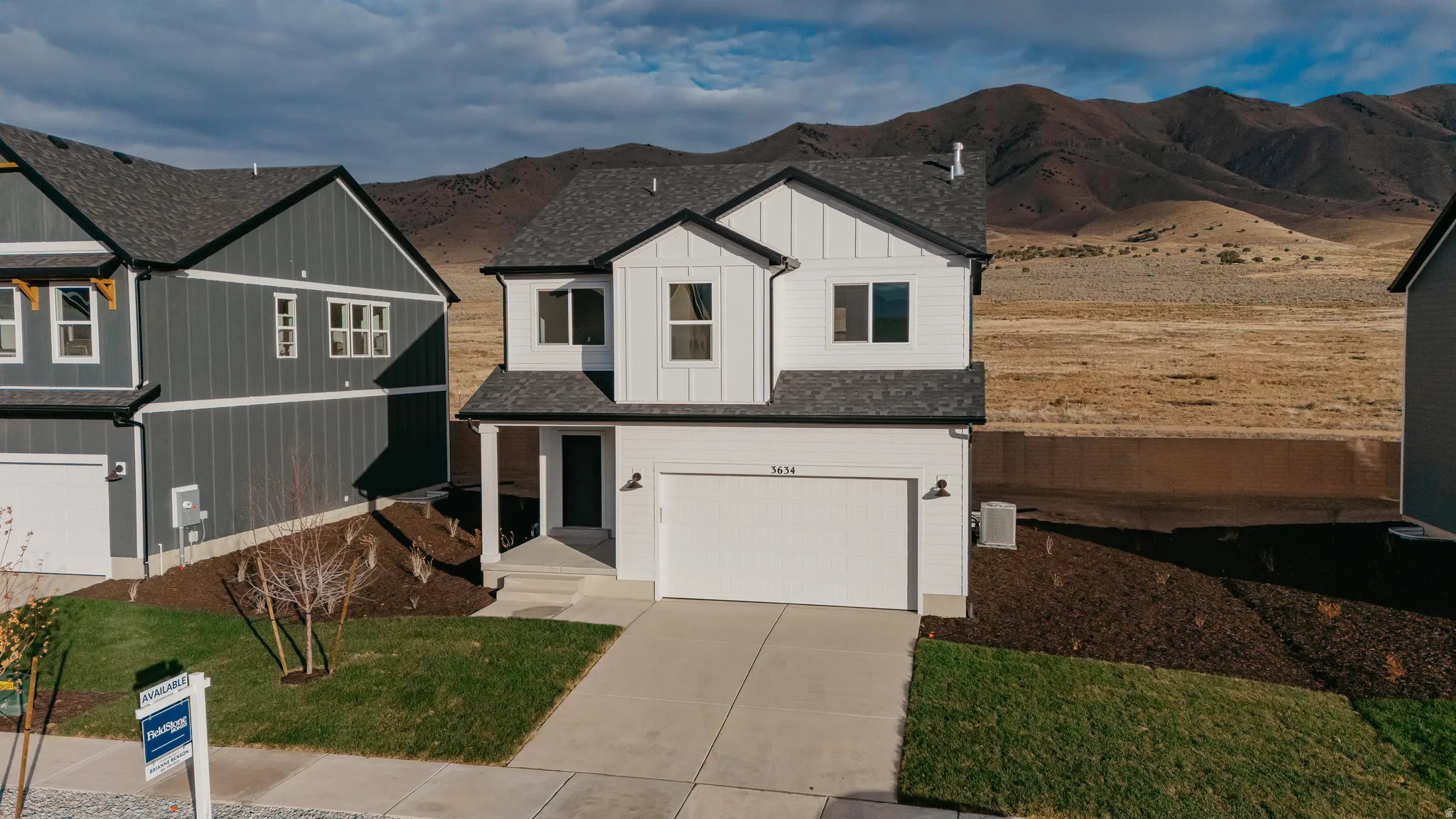 Contemporary two-story residence featuring a white exterior with dark trim accents, a two-car garage, and a covered entry