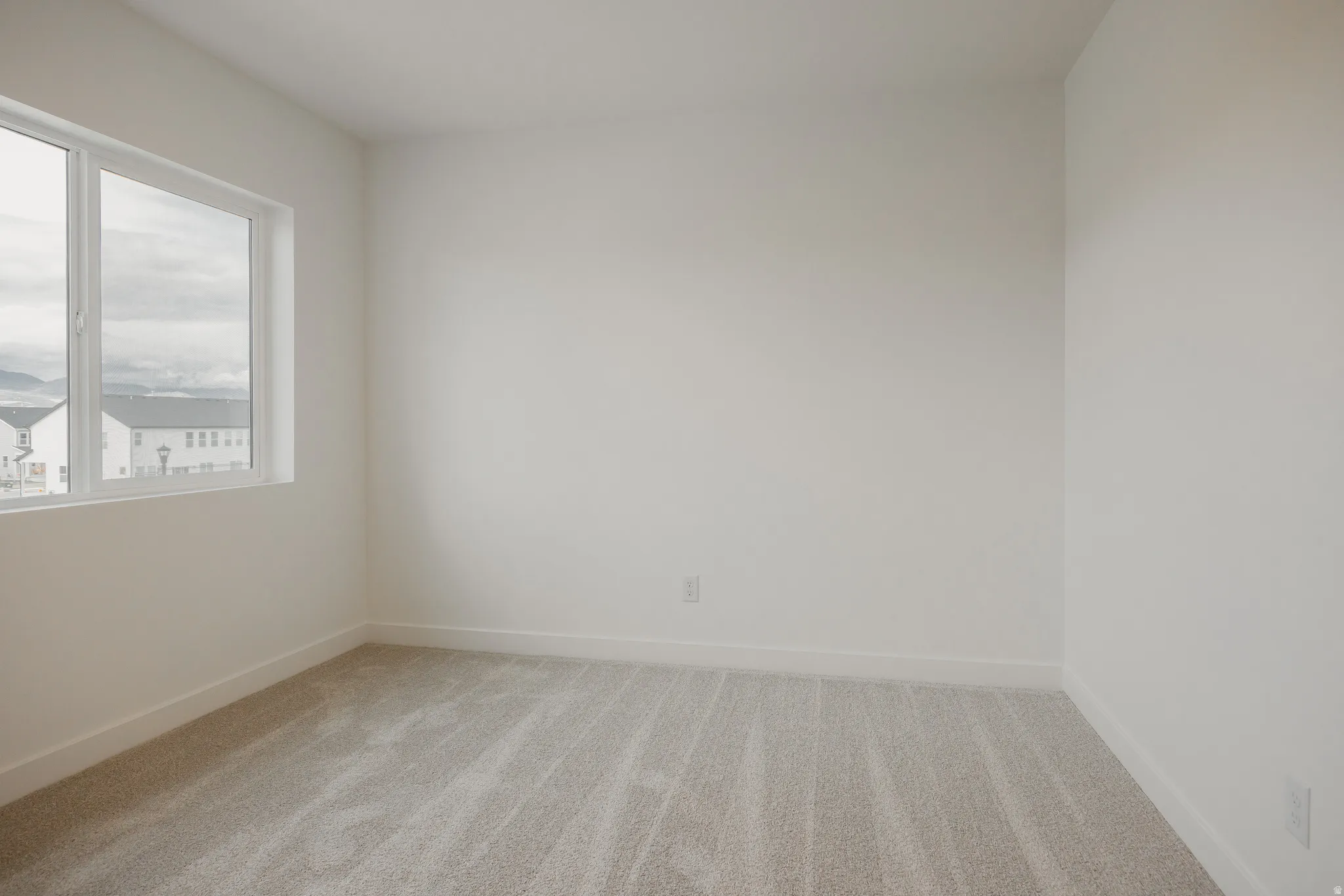 Light-filled interior space with a large window, neutral wall tones, and plush carpeting