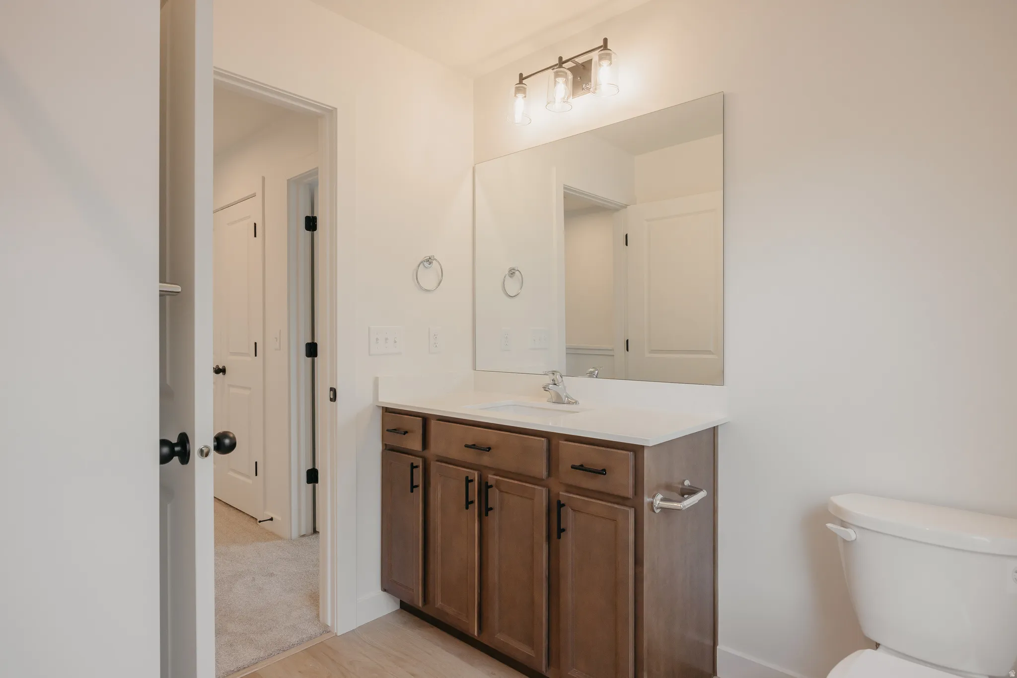 Bathroom featuring a single vanity with wood-finish cabinetry, a rectangular undermount sink, and a white countertop