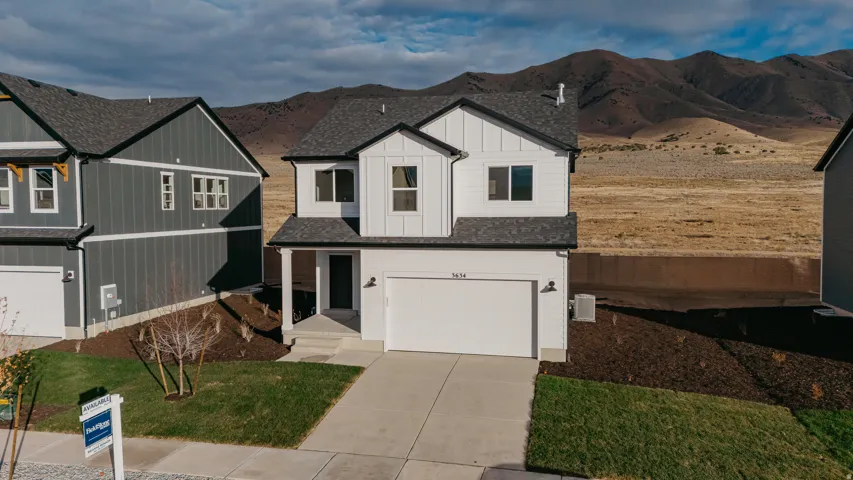 Contemporary two-story residence featuring a white exterior with dark trim accents, a two-car garage, and a covered entry