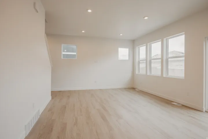 Spacious room featuring light wood-finish flooring, recessed lighting, multiple windows providing natural light, and a mountain backdrop